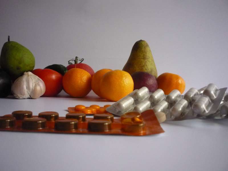 Birnen, Mandarinen, Tomaten und Knoblauchhinter Tablettenpackungen